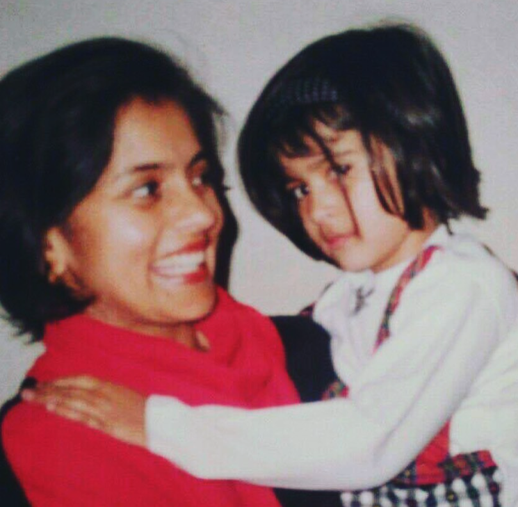 A young Kriti held in her mother's arms, the two smiling at each other.